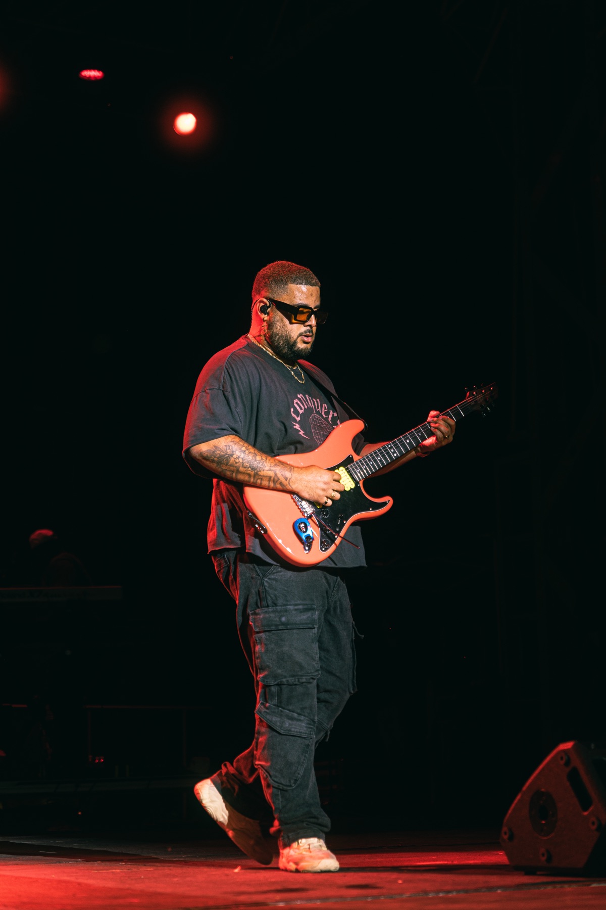 Toine performing live with guitar under red stage light